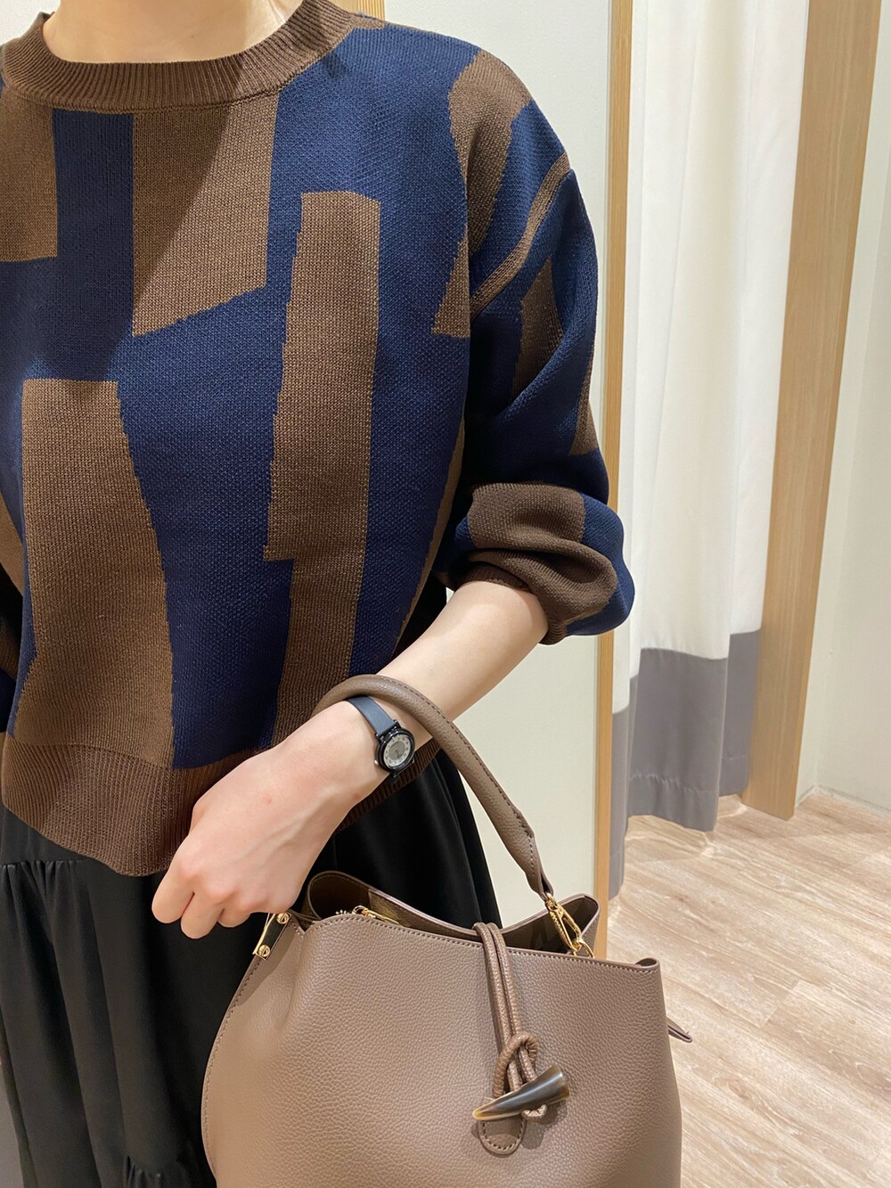 ブラック系のローファー、ブラック系のスカート、ブラウン系のハンドバッグを着用したレディースの秋コーディネートの2枚目の写真