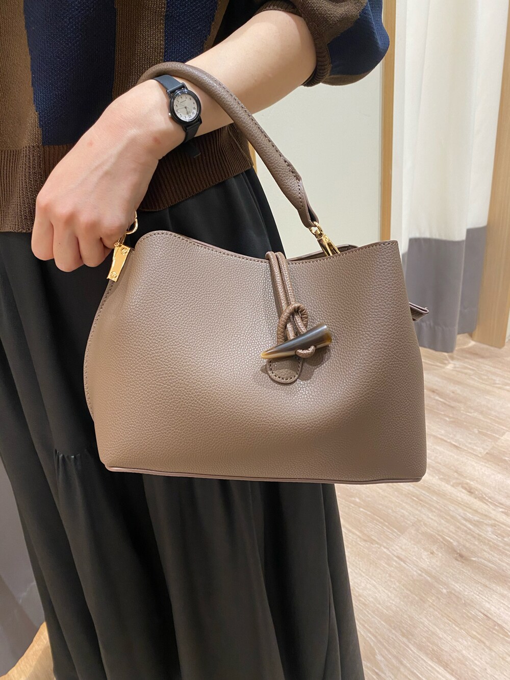 ブラック系のローファー、ブラック系のスカート、ブラウン系のハンドバッグを着用したレディースの秋コーディネートの4枚目の写真