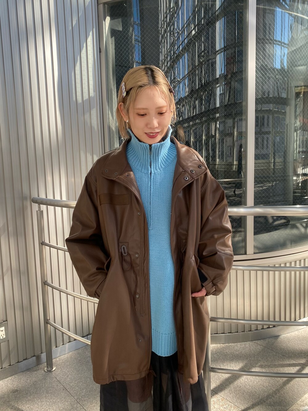 ブラウン系のモッズコート、ブルー系のニット/セーター、ブラック系のワンピースを着用したレディースの秋コーディネートの2枚目の写真