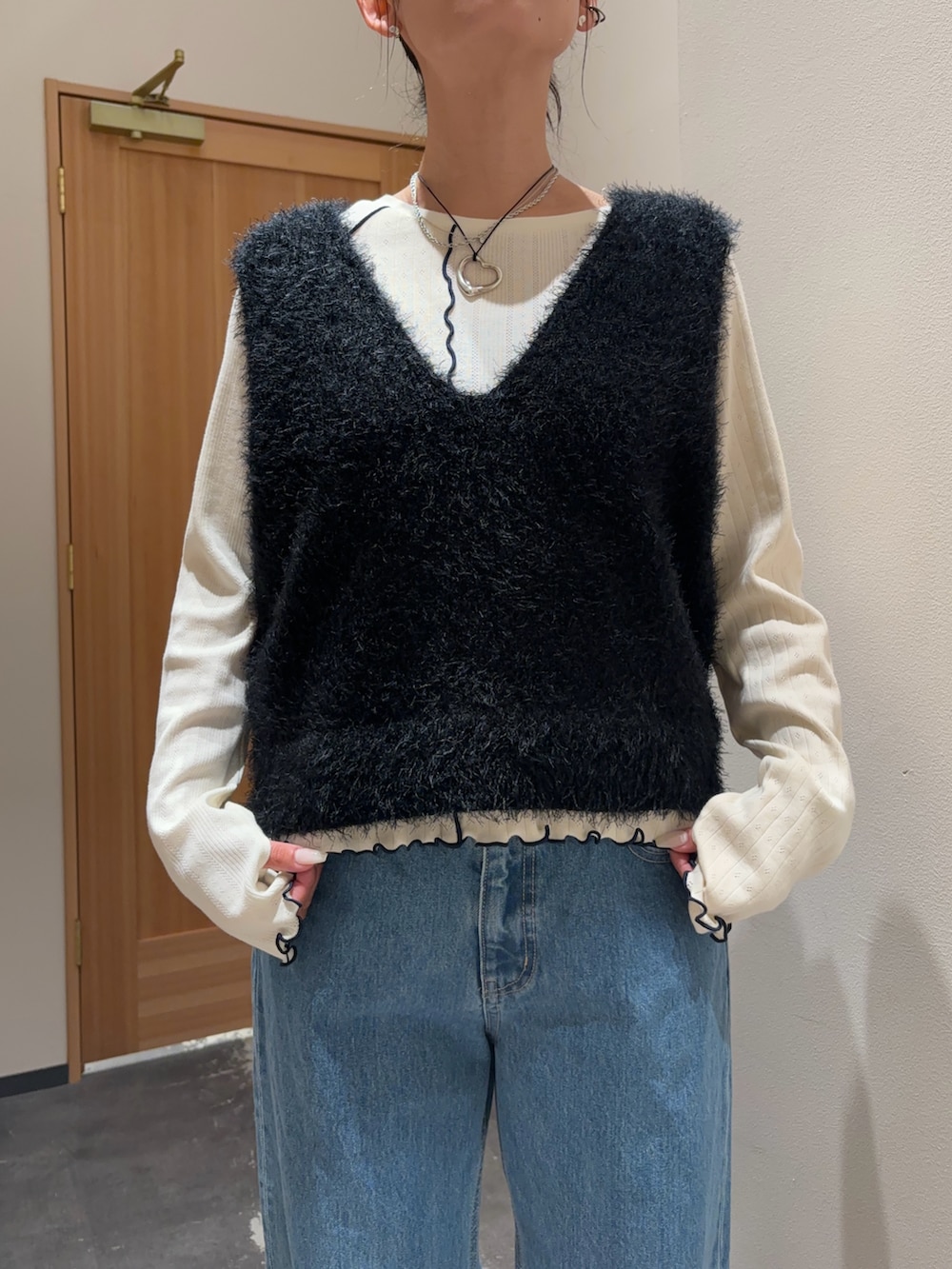 ブラック系のベスト、ホワイト系のTシャツ/カットソー、ブルー系のデニムパンツを着用したレディースの秋コーディネートの2枚目の写真