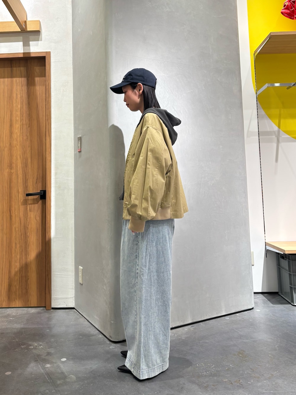 ベージュ系のトレンチコート、グレー系のパーカー、ブルー系のデニムパンツを着用したレディースの春コーディネートの3枚目の写真