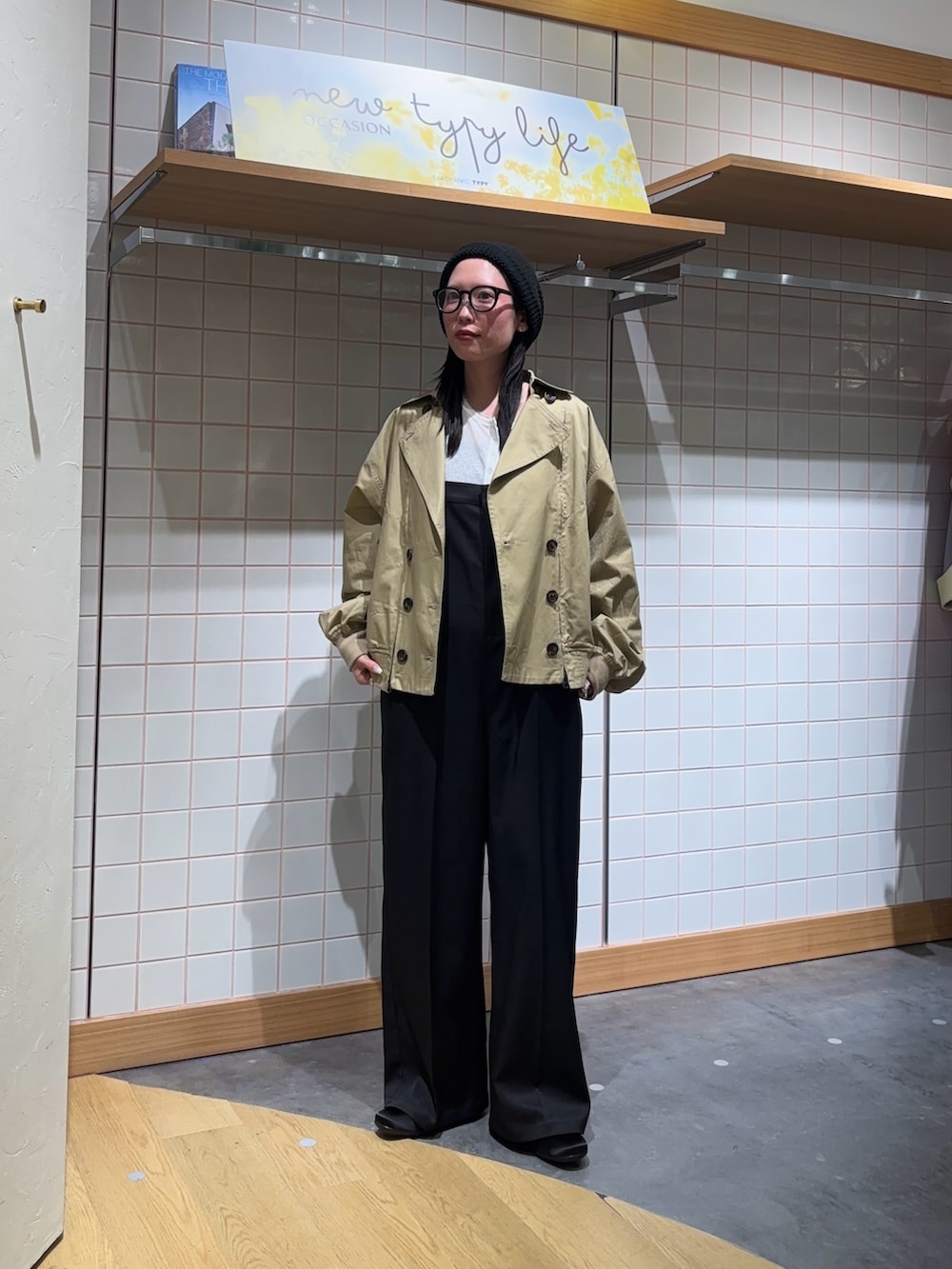 ベージュ系のトレンチコート、ホワイト系のTシャツ/カットソー、ブラック系のサロペット/オーバーオールを着用したレディースの春コーディネートの3枚目の写真