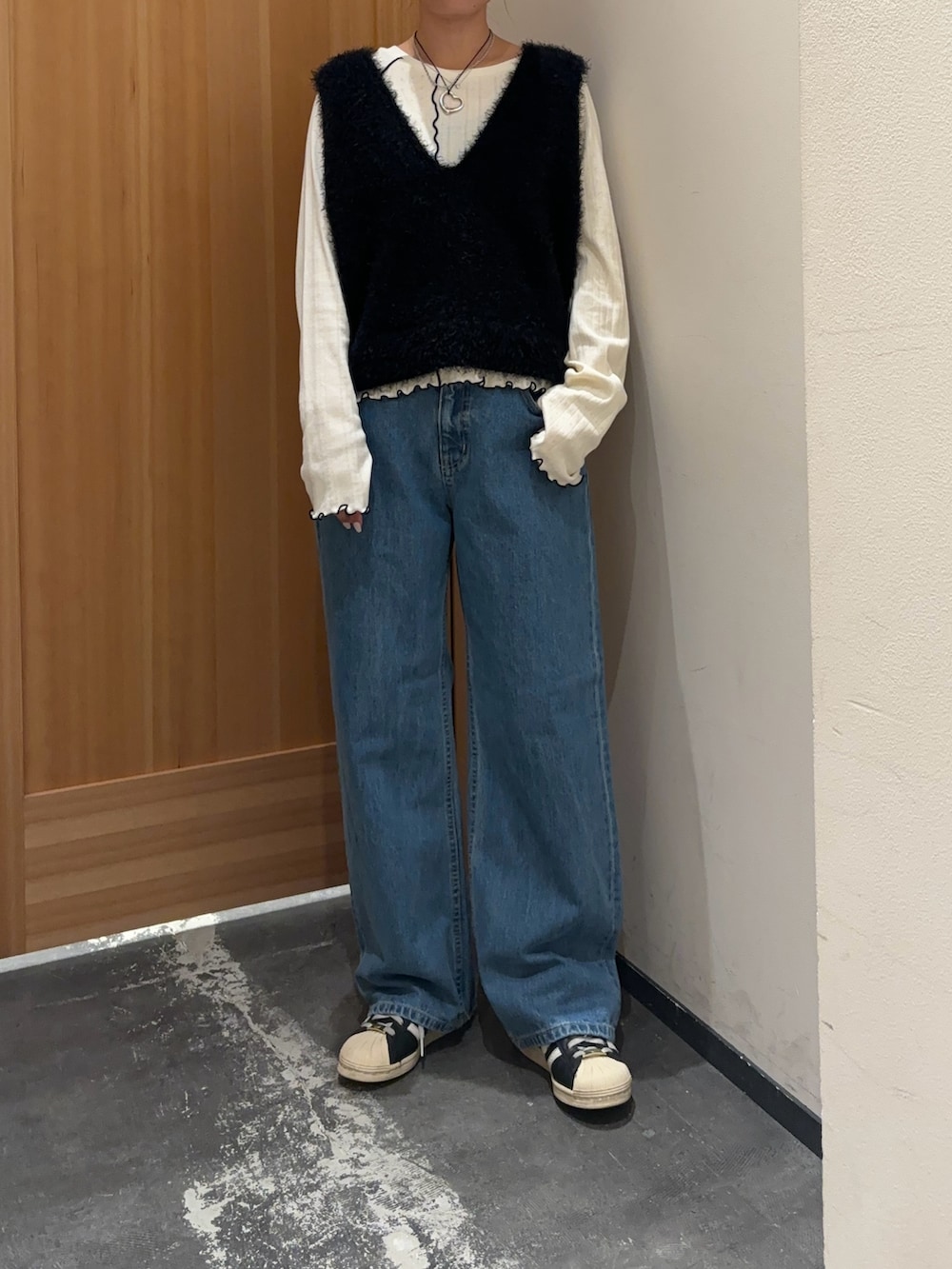 ブラック系のベスト、ホワイト系のTシャツ/カットソー、ブルー系のデニムパンツを着用したレディースの秋コーディネートの3枚目の写真