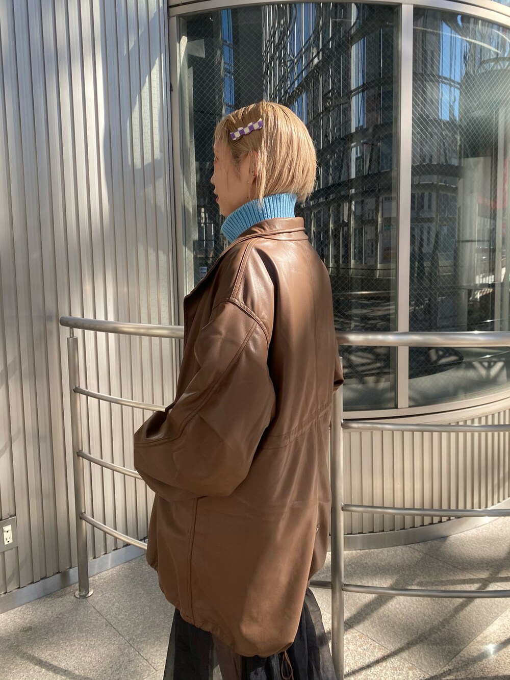 ブラウン系のモッズコート、ブルー系のニット/セーター、ブラック系のワンピースを着用したレディースの秋コーディネートの3枚目の写真