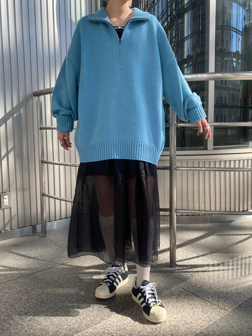 ブラウン系のモッズコート、ブルー系のニット/セーター、ブラック系のワンピースを着用したレディースの秋コーディネートの4枚目の写真