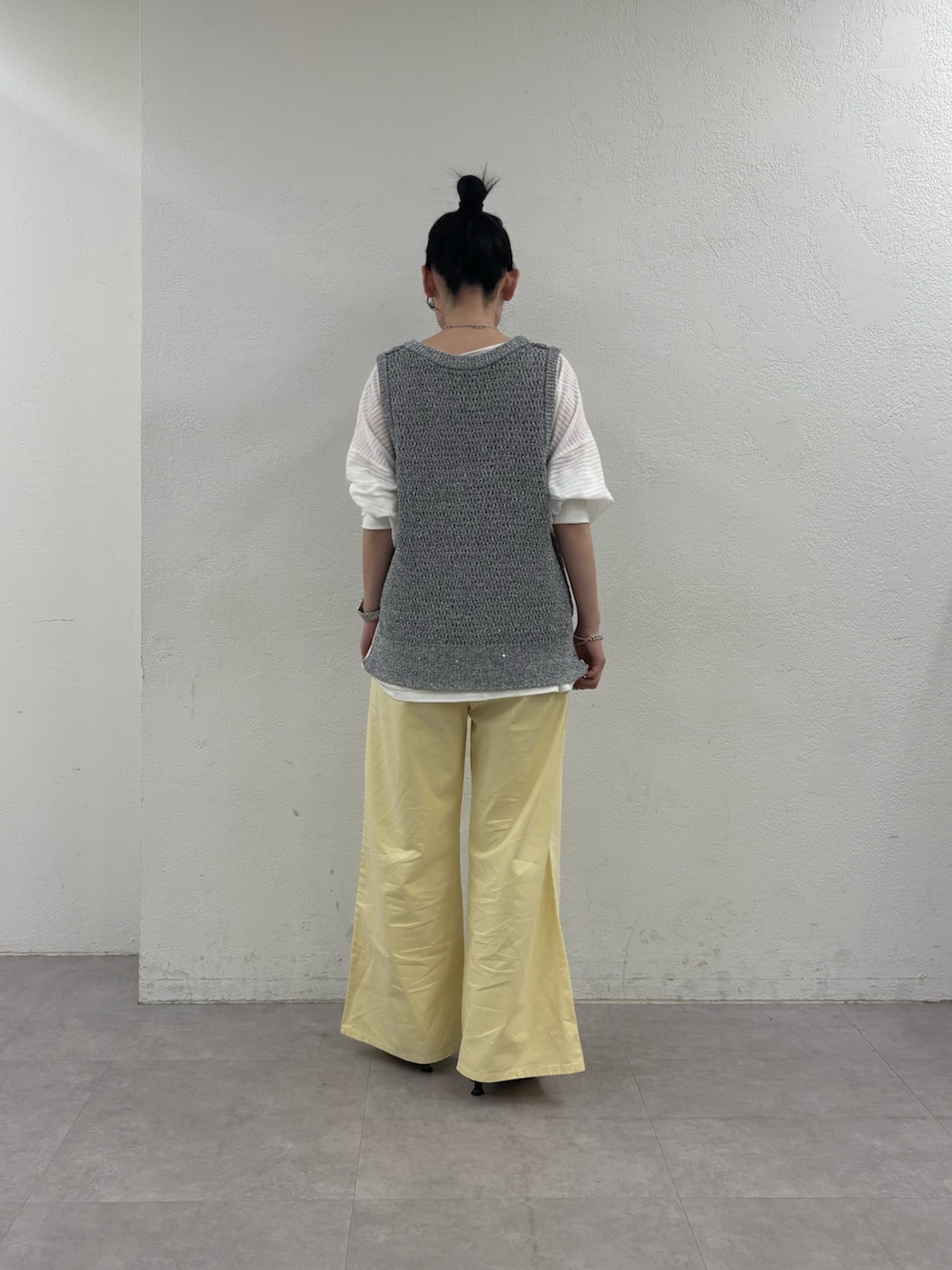 グレー系のベスト、ホワイト系のTシャツ/カットソー、イエロー系のデニムパンツを着用したレディースの春コーディネートの3枚目の写真