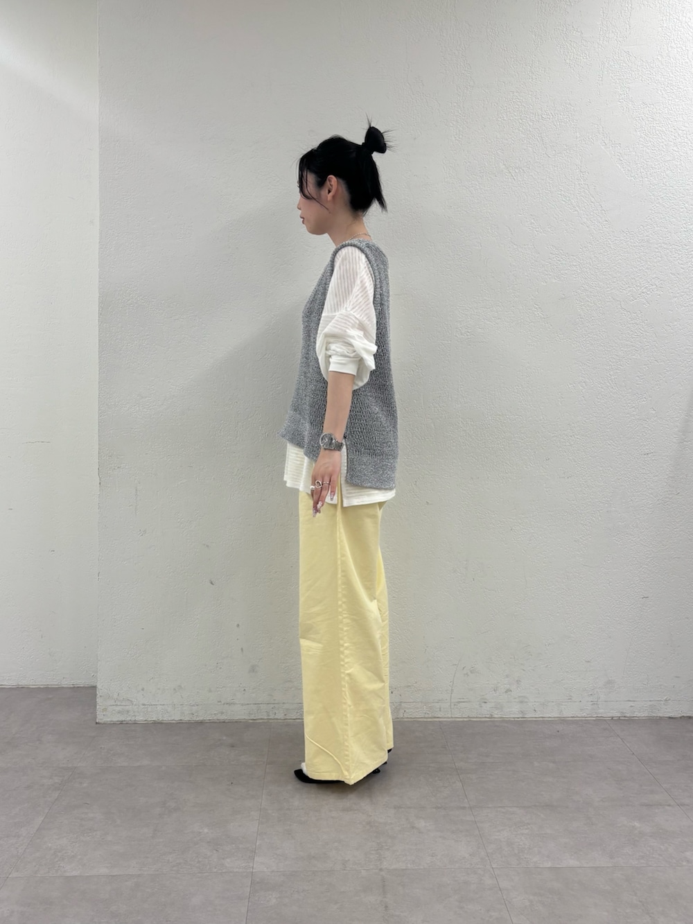 グレー系のベスト、ホワイト系のTシャツ/カットソー、イエロー系のデニムパンツを着用したレディースの春コーディネートの4枚目の写真