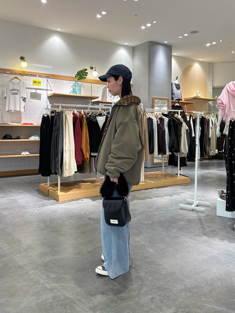 グリーン系のブルゾン、グレー系のTシャツ/カットソー、ブルー系のデニムパンツを着用したレディースの秋コーディネートの2枚目の写真