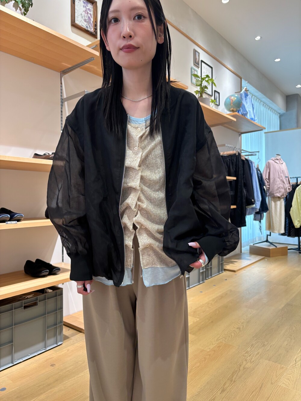 ブラック系のブルゾン、ベージュ系のカーディガン/ボレロ、ベージュ系のスラックスを着用したレディースの春コーディネートの7枚目の写真