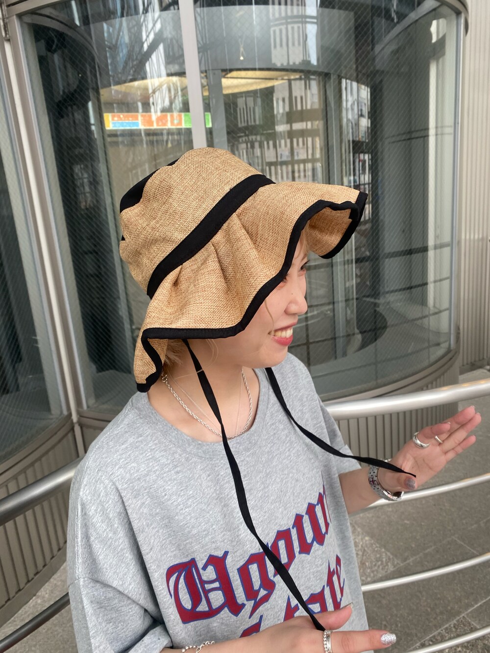 レッド系のスカート、グレー系のTシャツ/カットソー、ブラック系のハットを着用したレディースの夏コーディネートの4枚目の写真