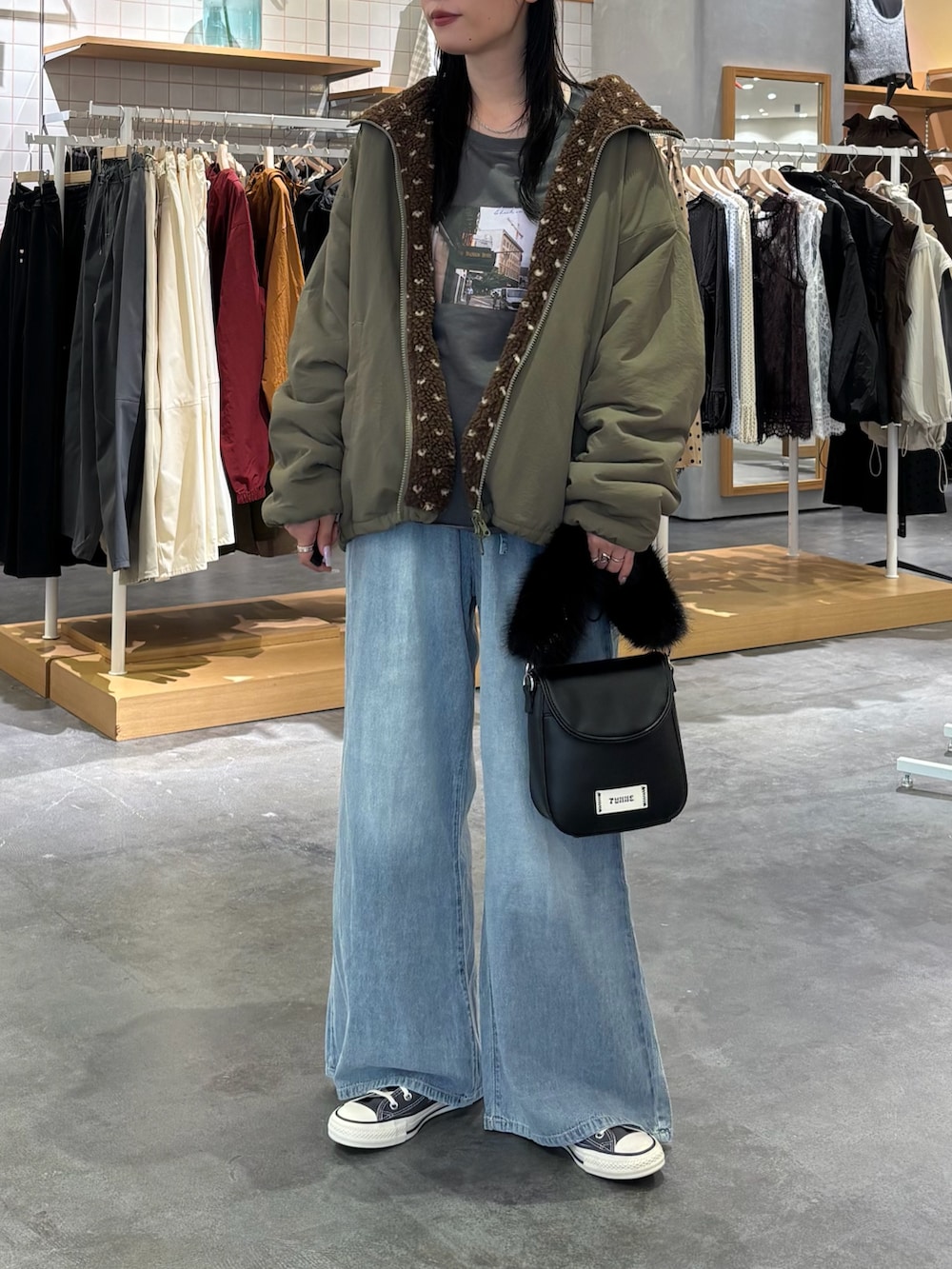 グリーン系のブルゾン、グレー系のTシャツ/カットソー、ブルー系のデニムパンツを着用したレディースの秋コーディネートの3枚目の写真