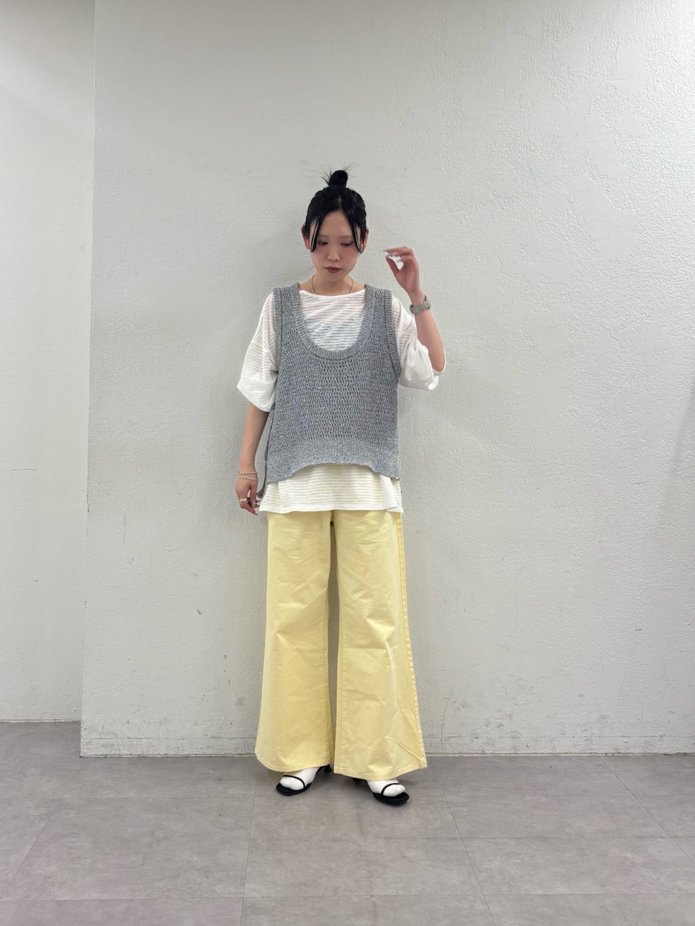 グレー系のベスト、ホワイト系のTシャツ/カットソー、イエロー系のデニムパンツを着用したレディースの春コーディネートの2枚目の写真