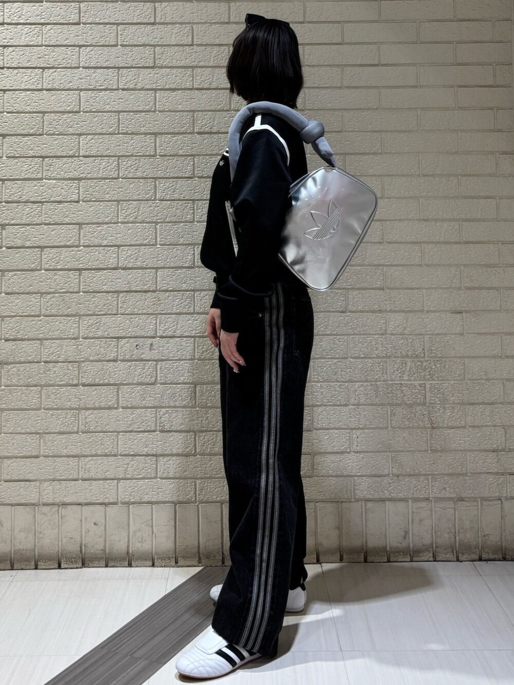 ブラック系のナイロンジャケット、ブラック系のデニムパンツ、シルバー系のショルダーバッグを着用したレディースの冬コーディネートの2枚目の写真