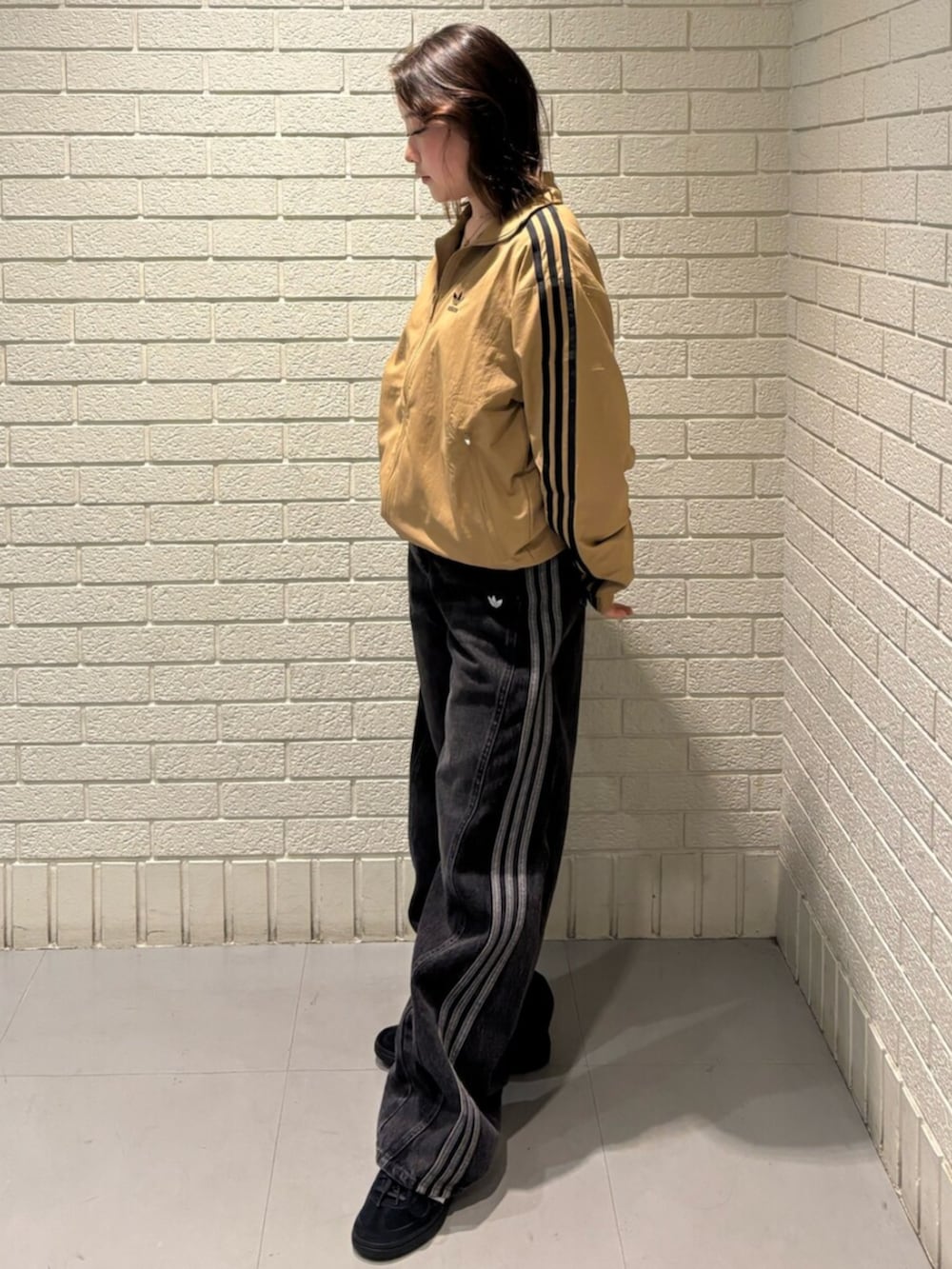 ブラウン系のナイロンジャケット、ブラック系のパンツ、ブラック系のスニーカーを着用したレディースの秋コーディネートの2枚目の写真