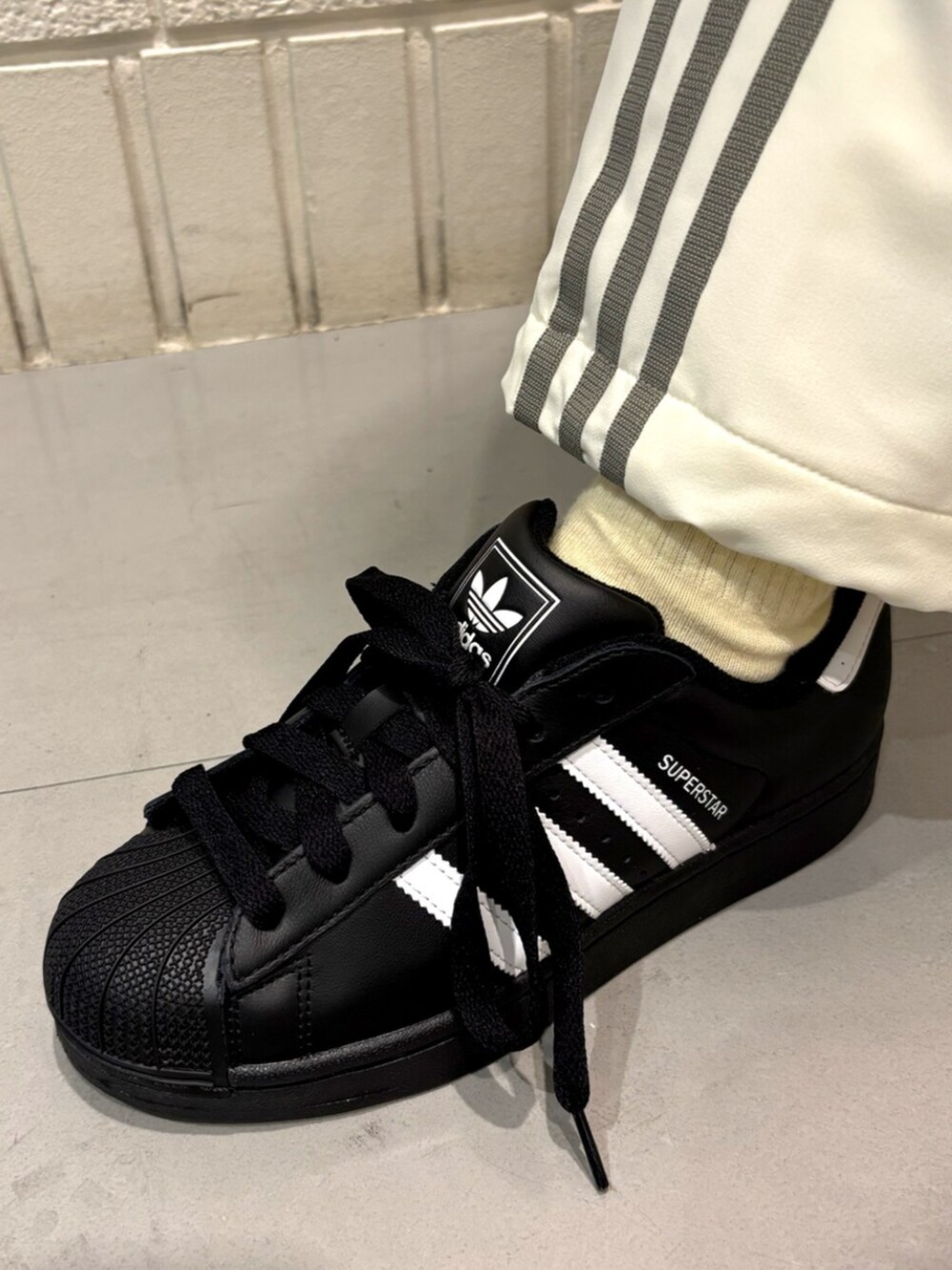 ブラック系のTシャツ/カットソー、ホワイト系のその他パンツ、ブラック系のスニーカーを着用したレディースの春コーディネートの4枚目の写真