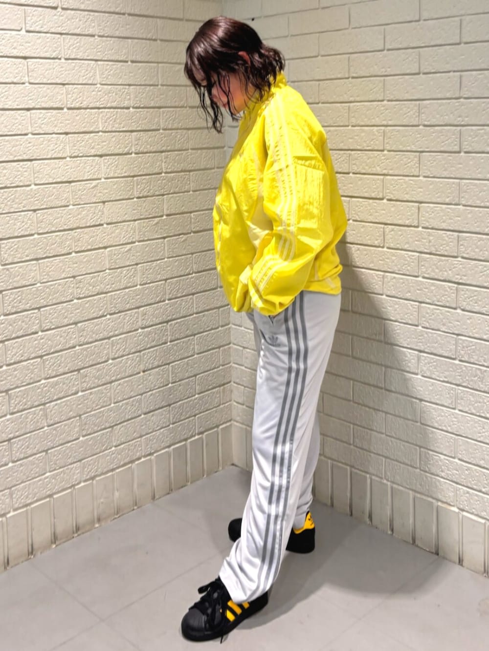 イエロー系のトップス、グレー系のスウェットパンツ、ブラック系のスニーカーを着用したレディースの春コーディネートの2枚目の写真