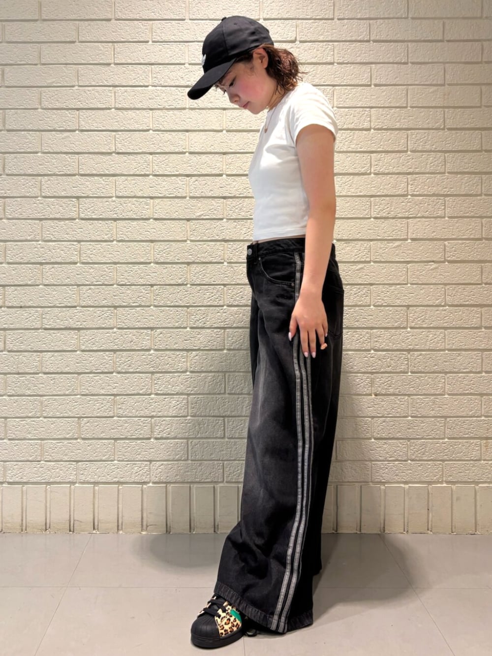 ブラック系のデニムパンツ、ブラック系のスニーカー、ブラック系のキャップを着用したレディースの夏コーディネートの2枚目の写真