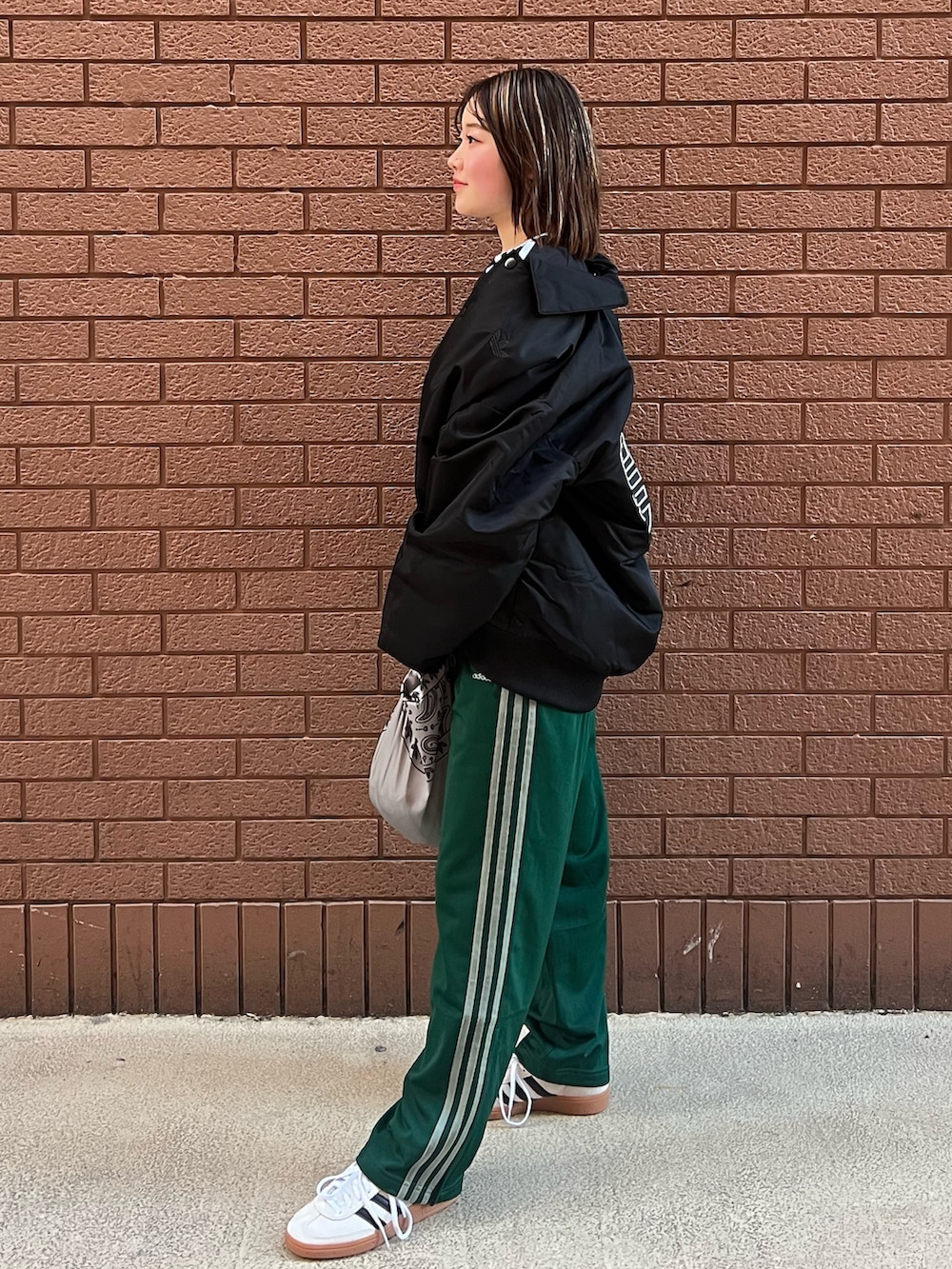 ベージュ系のスニーカー、ブラック系のTシャツ/カットソー、グリーン系のスウェットパンツを着用したレディースの冬コーディネートの2枚目の写真