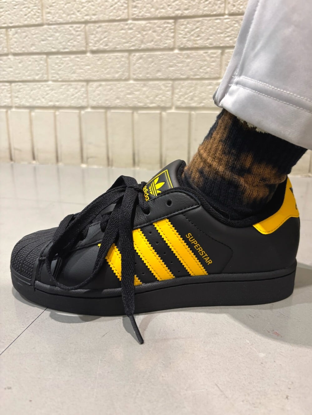 イエロー系のトップス、グレー系のスウェットパンツ、ブラック系のスニーカーを着用したレディースの春コーディネートの4枚目の写真