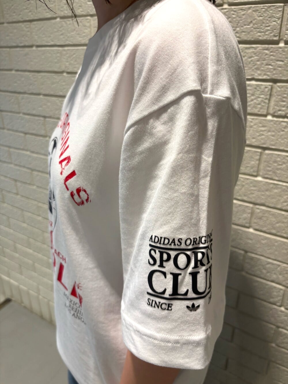 ホワイト系のトップス、ブルー系のスニーカーを着用したレディースの夏コーディネートの3枚目の写真