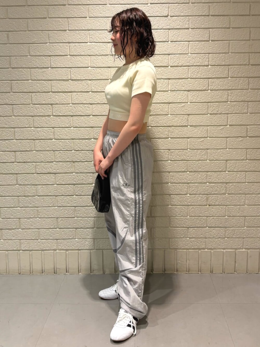 ブラック系のハンドバッグ、ホワイト系のスニーカー、ホワイト系のTシャツ/カットソーを着用したレディースの夏コーディネートの2枚目の写真