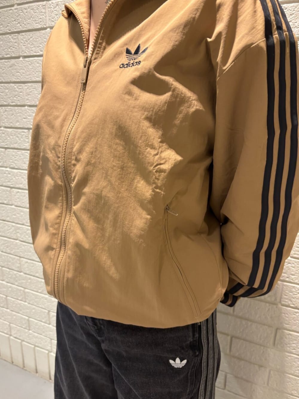 ブラウン系のナイロンジャケット、ブラック系のパンツ、ブラック系のスニーカーを着用したレディースの秋コーディネートの3枚目の写真