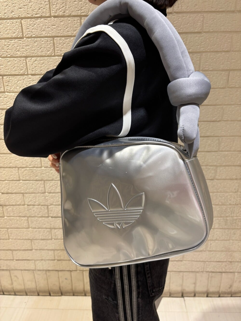 ブラック系のナイロンジャケット、ブラック系のデニムパンツ、シルバー系のショルダーバッグを着用したレディースの冬コーディネートの3枚目の写真