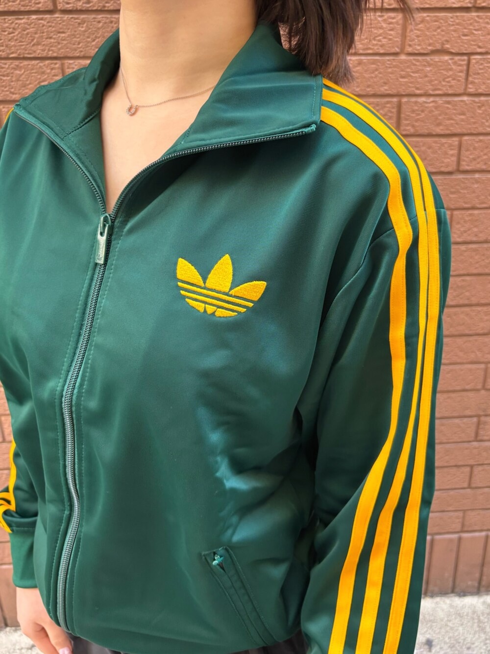 グリーン系のジャージ、ブラック系のその他パンツ、ブラック系のスニーカーを着用したレディースの春コーディネートの3枚目の写真