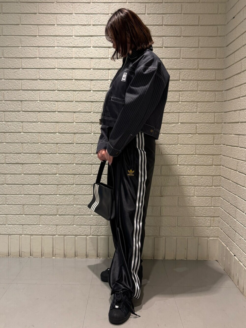 ブラック系のその他パンツ、ブラック系のスニーカー、ブラック系のショルダーバッグを着用したレディースの春コーディネートの2枚目の写真