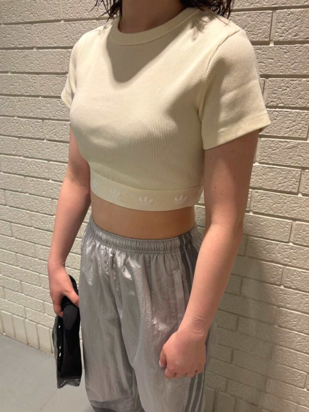 ブラック系のハンドバッグ、ホワイト系のスニーカー、ホワイト系のTシャツ/カットソーを着用したレディースの夏コーディネートの3枚目の写真