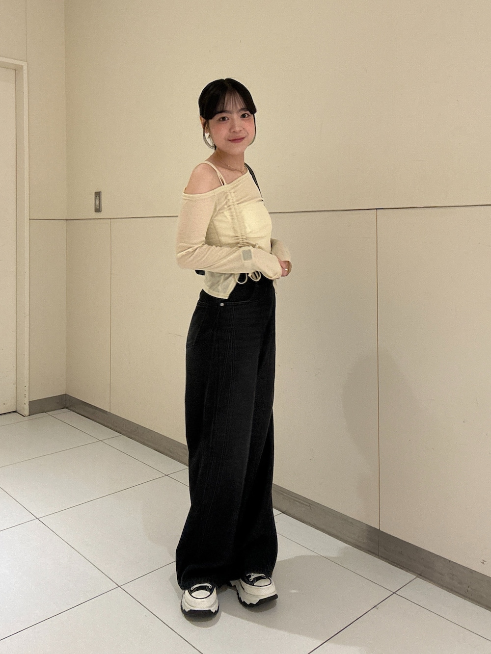 ベージュ系のTシャツ/カットソー、ブラック系のデニムパンツを着用したレディースの秋コーディネートの3枚目の写真