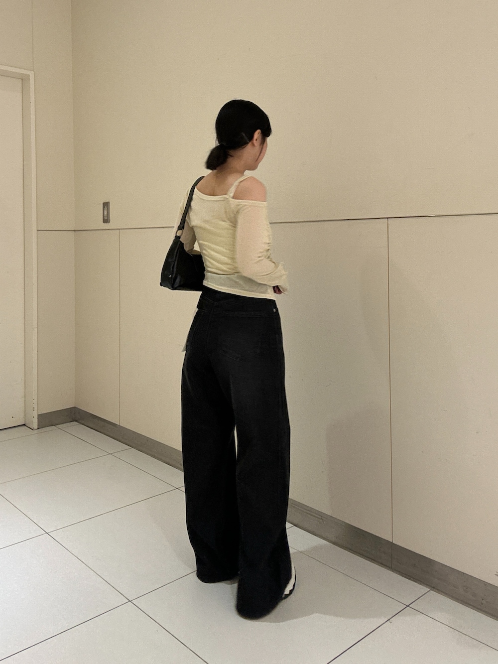 ベージュ系のTシャツ/カットソー、ブラック系のデニムパンツを着用したレディースの秋コーディネートの2枚目の写真