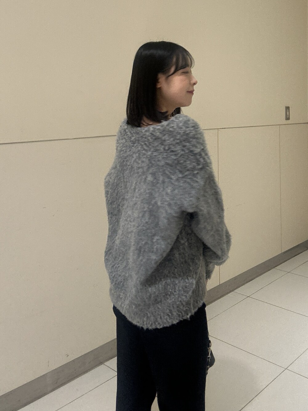 グレー系のニット/セーター、ブルー系のデニムパンツを着用したレディースの秋コーディネートの4枚目の写真