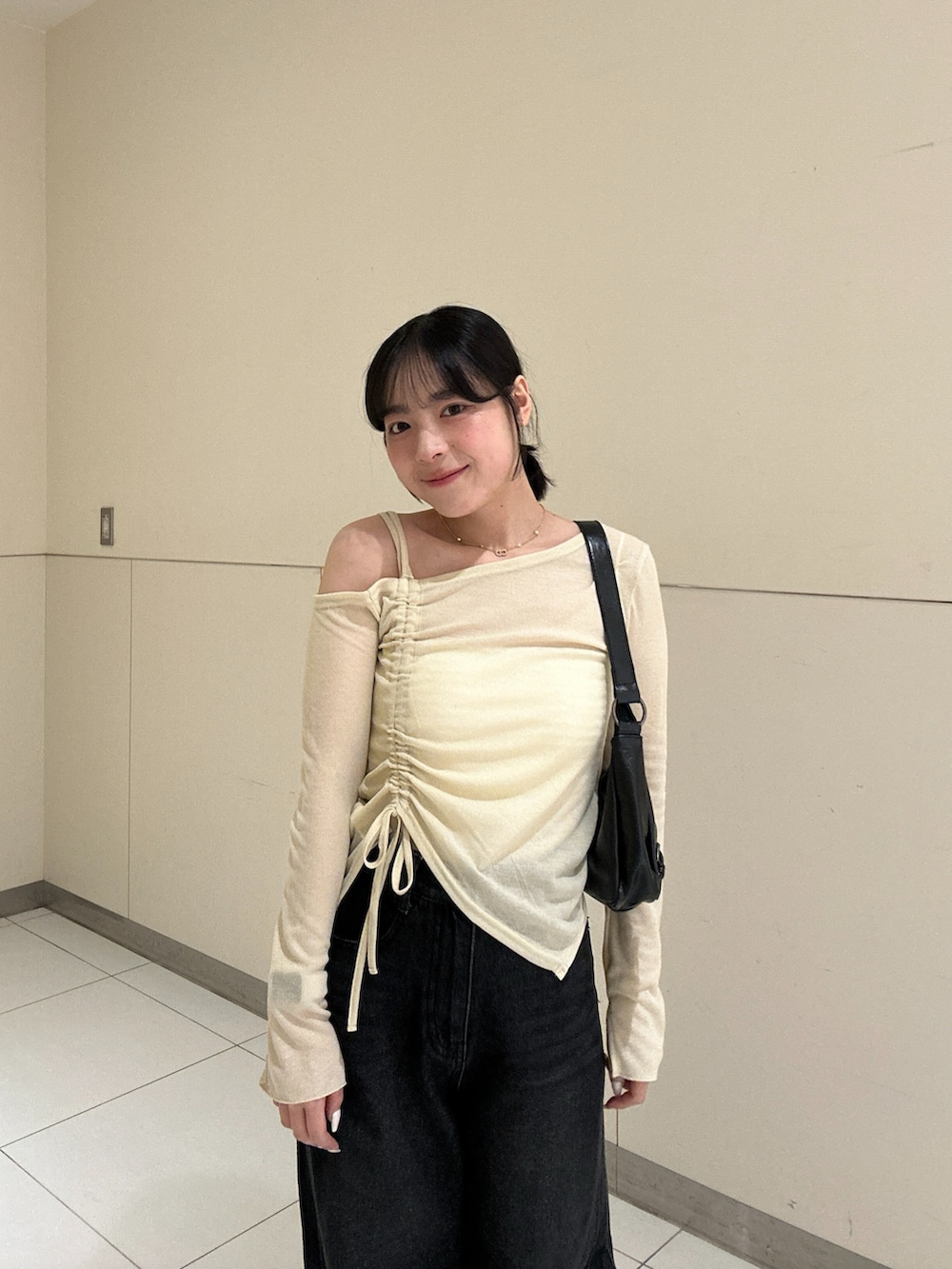 ベージュ系のTシャツ/カットソー、ブラック系のデニムパンツを着用したレディースの秋コーディネートの4枚目の写真