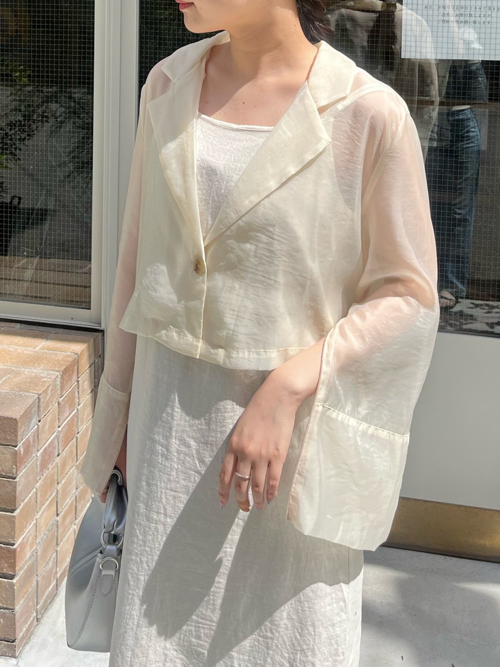 ブラック系のショルダーバッグ、ホワイト系のテーラードジャケットを着用したレディースの夏コーディネートの3枚目の写真