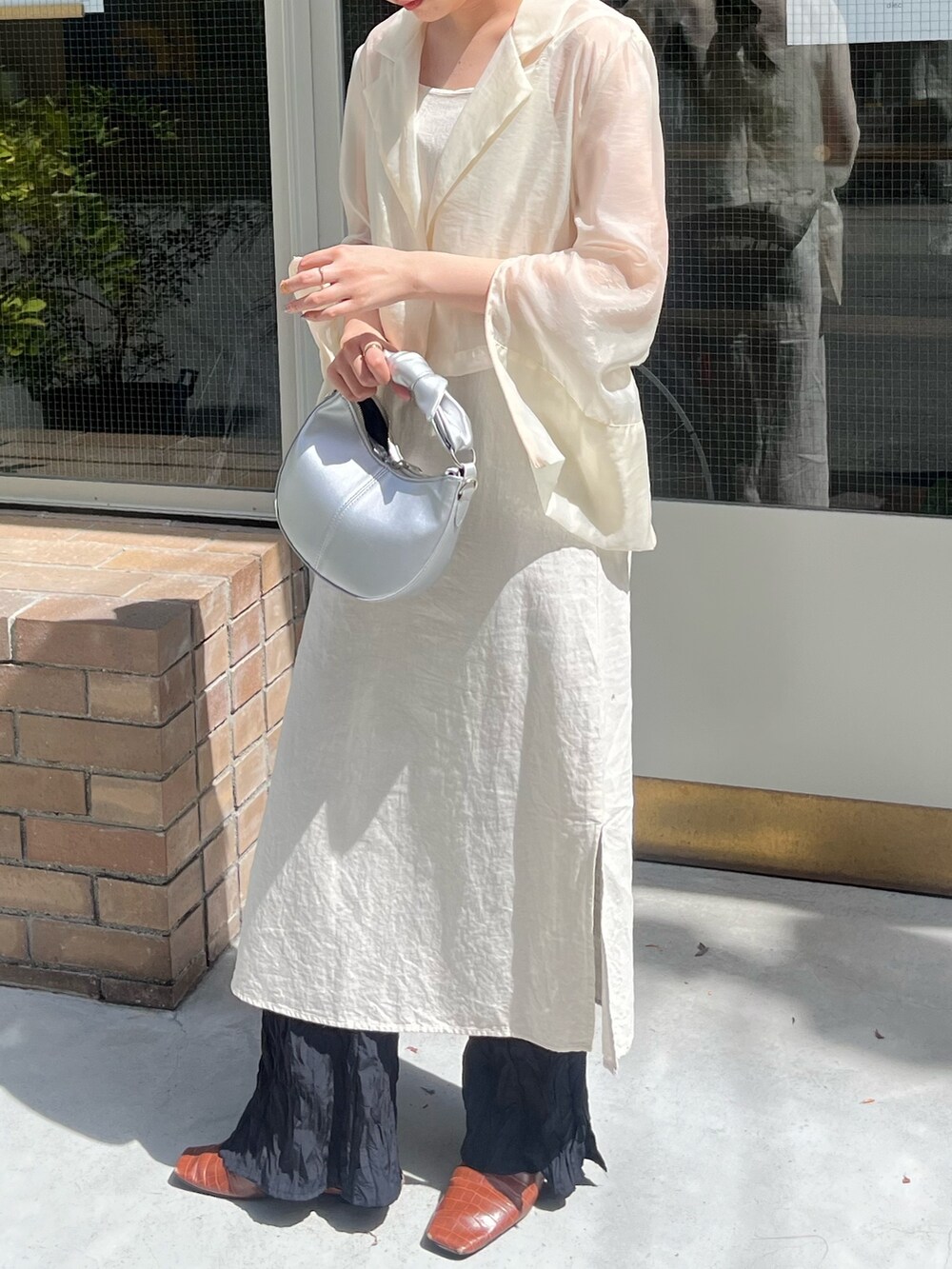 ブラック系のショルダーバッグ、ホワイト系のテーラードジャケットを着用したレディースの夏コーディネートの2枚目の写真