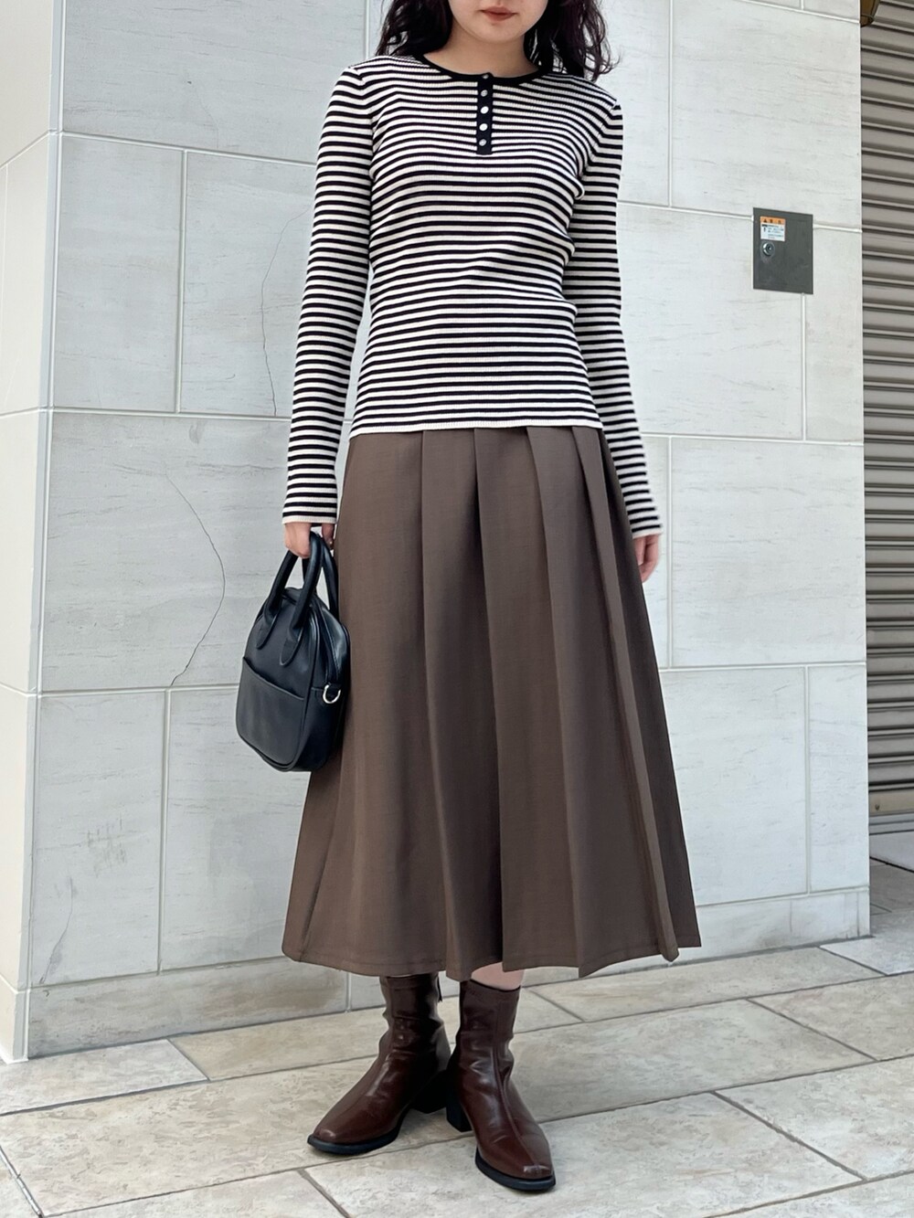ブラック系のTシャツ/カットソー、ブラウン系のスカートを着用したレディースの秋コーディネートの2枚目の写真