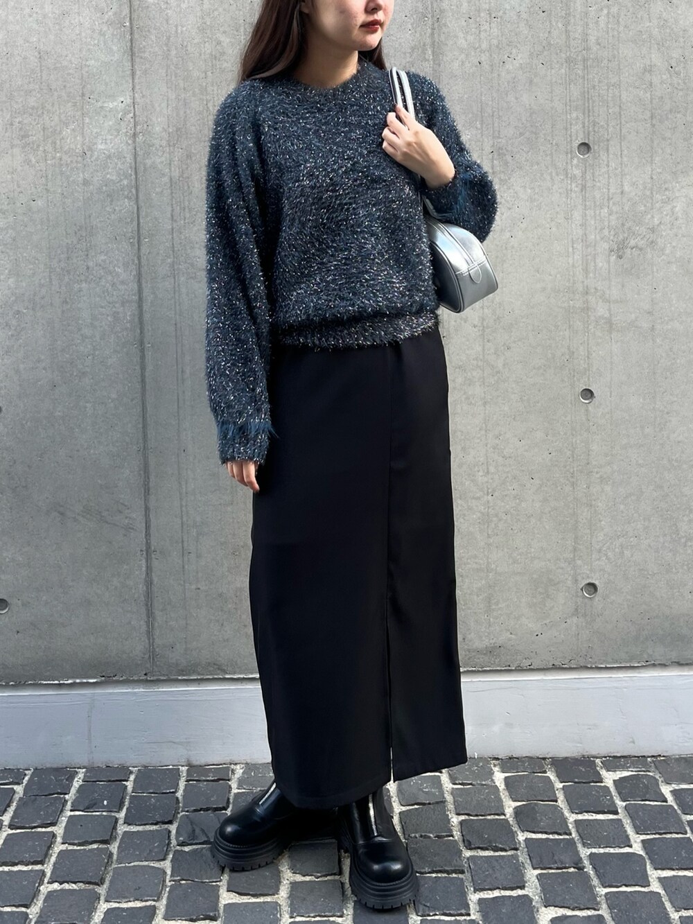 ブラック系のブーツ、シルバー系のショルダーバッグ、ブルー系のニット/セーターを着用したレディースの冬コーディネートの2枚目の写真