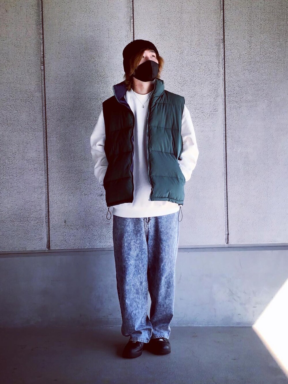 ホワイト系のスウェット、グリーン系のダウンベスト、ブルー系のデニムパンツを着用したメンズの秋コーディネートの2枚目の写真