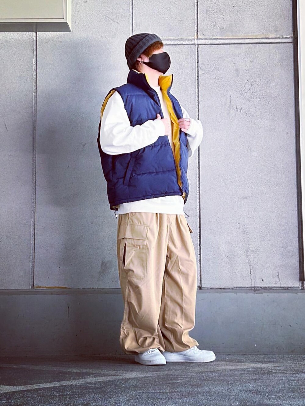 ブルー系のダウンベスト、ベージュ系のカーゴパンツ、ホワイト系のスニーカーを着用したメンズの冬コーディネートの2枚目の写真