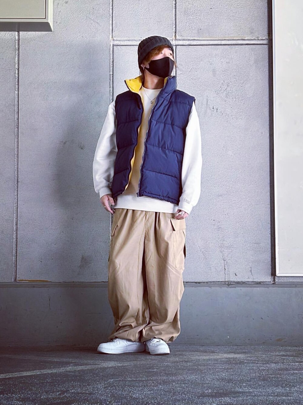 ブルー系のダウンベスト、ベージュ系のカーゴパンツ、ホワイト系のスニーカーを着用したメンズの冬コーディネートの3枚目の写真