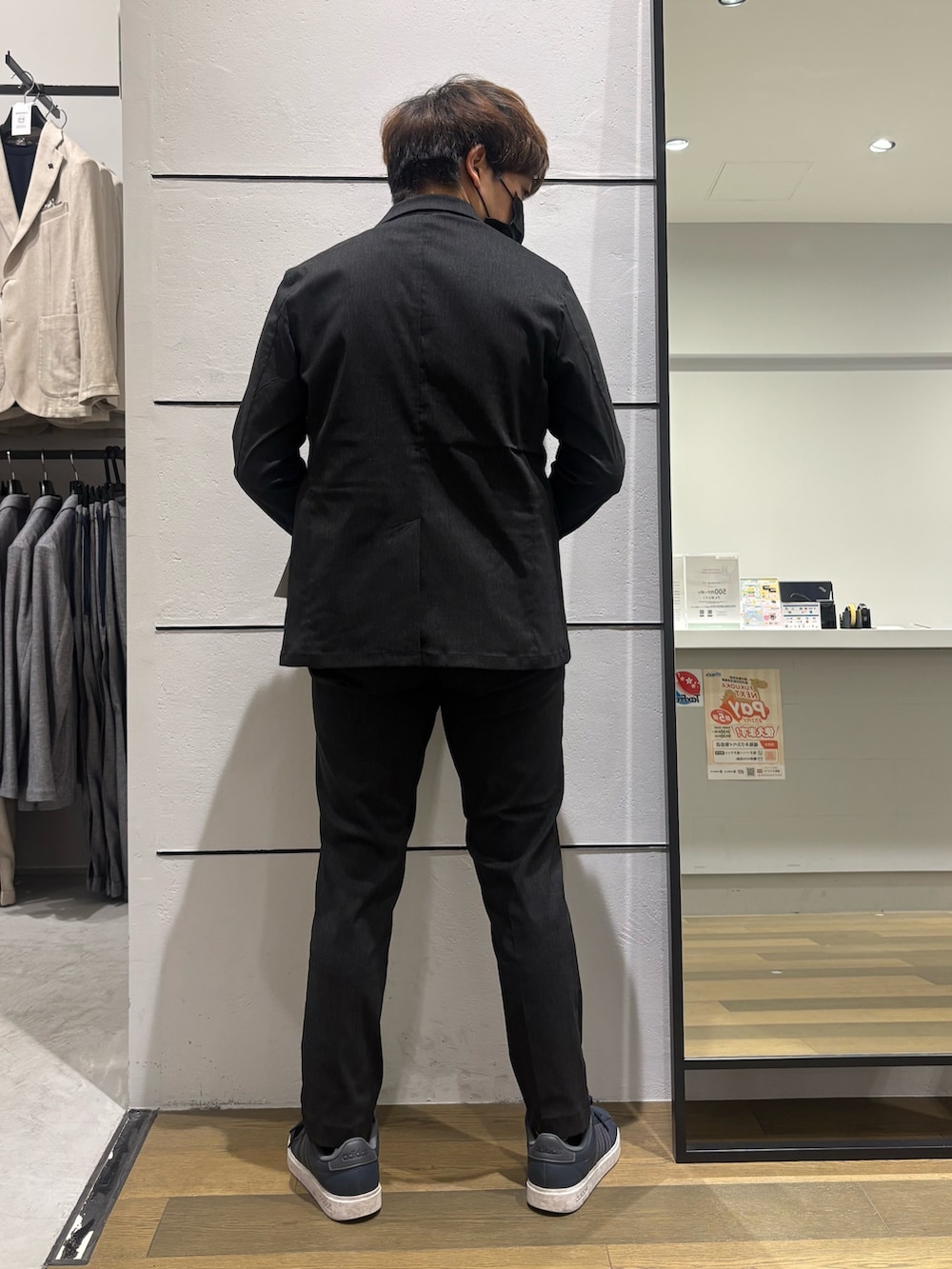ブラック系のテーラードジャケット、ベージュ系のTシャツ/カットソー、ブラック系のスラックスを着用したメンズの春コーディネートの2枚目の写真