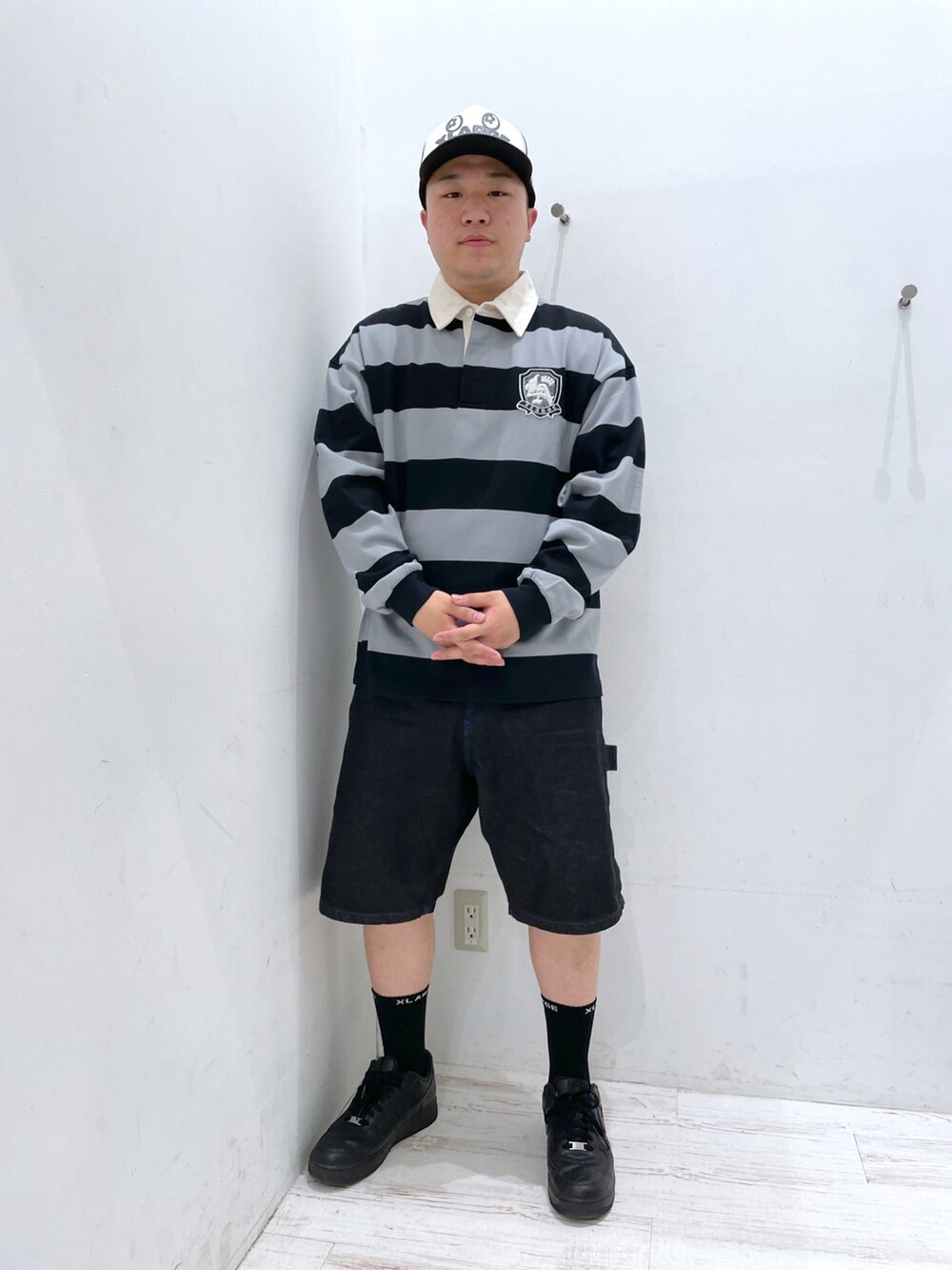 ブラック系のポロシャツ、ブラック系のキャップを着用したメンズの春コーディネートの2枚目の写真