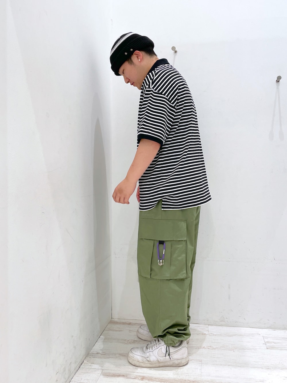 ブラック系のポロシャツ、グリーン系のカーゴパンツ、ブラック系のニットキャップ/ビーニーを着用したメンズの夏コーディネートの2枚目の写真