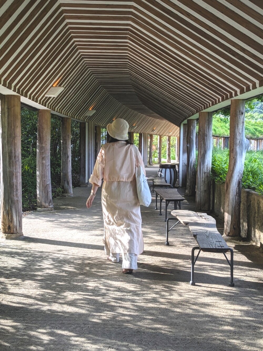 ピンク系のワンピース、ベージュ系のパンツ、ホワイト系のトートバッグを着用したレディースの夏コーディネートの2枚目の写真