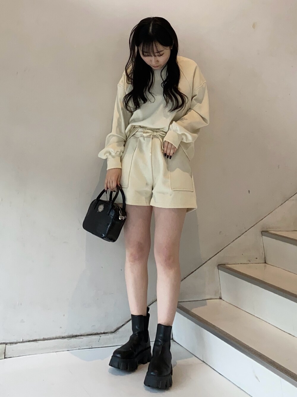 ホワイト系のスウェット、ブラック系のショルダーバッグ、ブラック系のブーツを着用したレディースの冬コーディネートの2枚目の写真