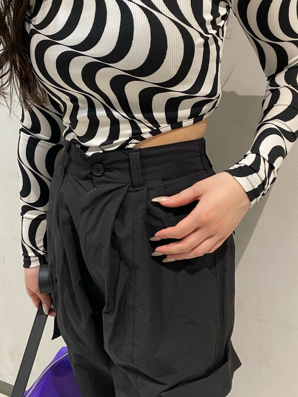 ブラック系のTシャツ/カットソー、パープル系のハンドバッグ、ブラック系のブーツを着用したレディースの春コーディネートの4枚目の写真