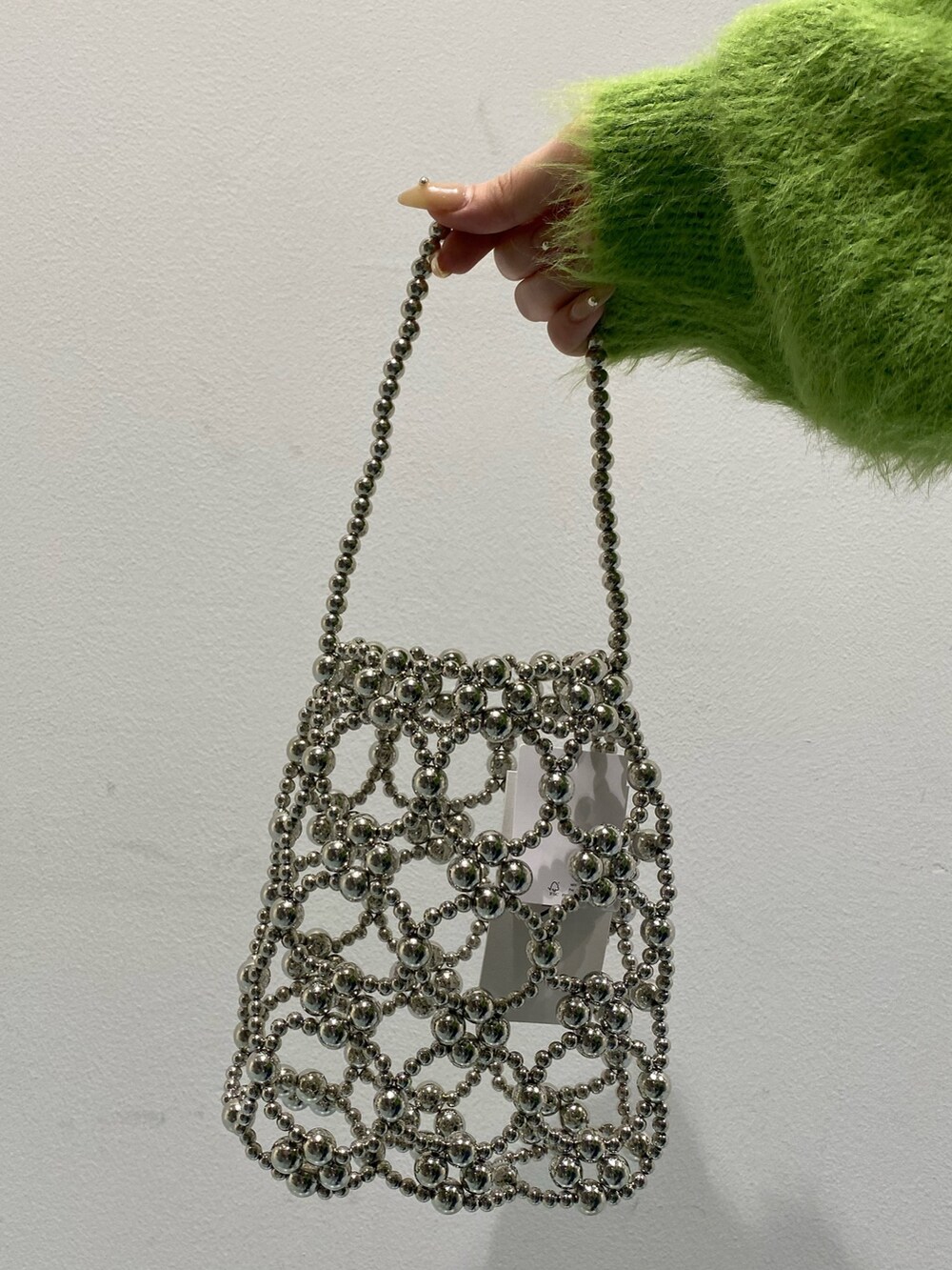 グリーン系のニット/セーター、ブルー系のデニムスカート、ブラック系のブーツを着用したレディースの冬コーディネートの6枚目の写真