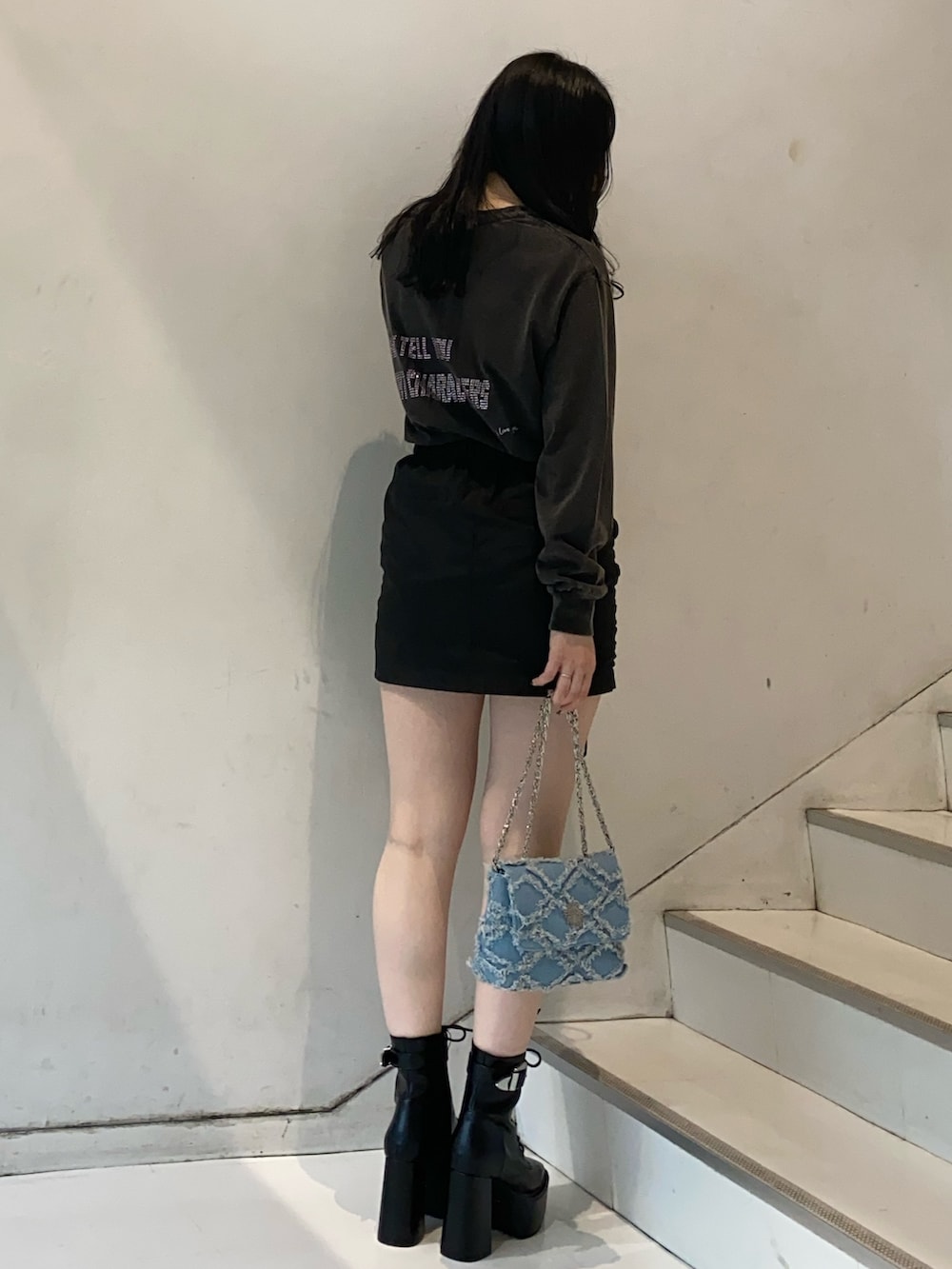 グレー系のTシャツ/カットソー、ブラック系のスカート、ブルー系のショルダーバッグを着用したレディースの冬コーディネートの2枚目の写真