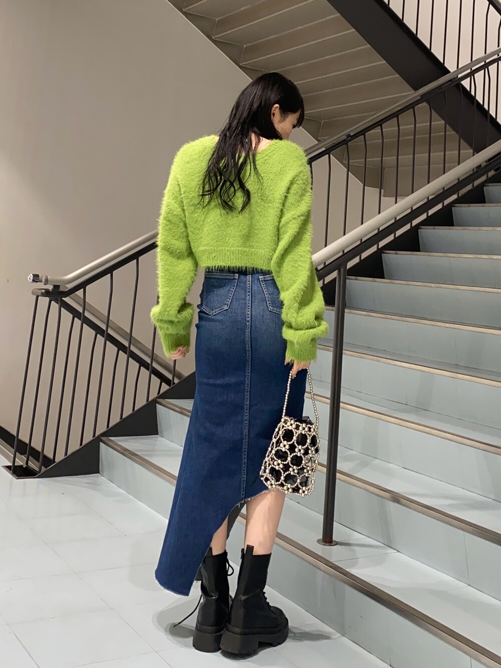 グリーン系のニット/セーター、ブルー系のデニムスカート、ブラック系のブーツを着用したレディースの冬コーディネートの2枚目の写真